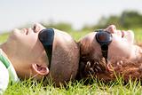 Happy couple laying on a lawn and looks 