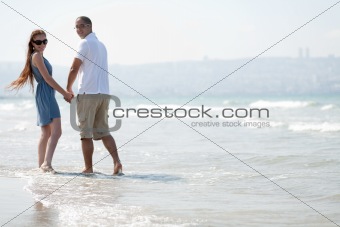 Lovely Couple walking at the beach and look back