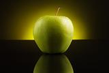 Green apple with drops on yellow background