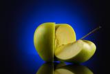 Green quarter and three quarters apple with on blue background