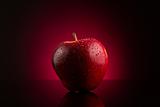 Red apple with water drops on dark red background