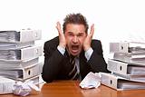 Stressed business man screams frustrated in office between folde