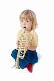 boy with long blond hair playing with toy trumpet