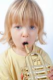 boy with long blond hair playing with toy trumpet