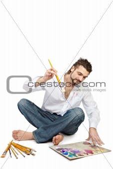 Man with brushes sitting near palette. Isolated over white