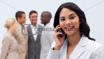 Ethnic businesswoman on phone with her team in the background