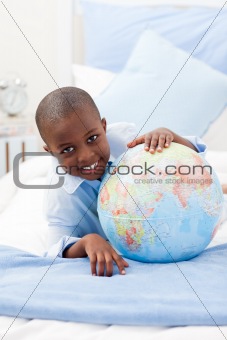 Boy looking at a globe while smiling at the camera