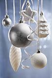Silver and white Christmas ornaments over blue