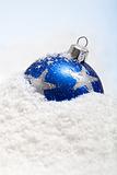 One blue christmas bauble in the snow