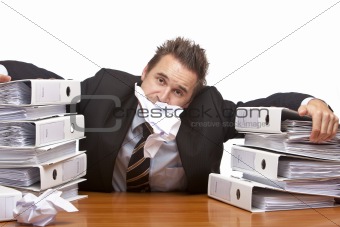 Stressed business man is frustrated in office between folder sta