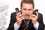 Stressed business man  with two telephones is crying in office 