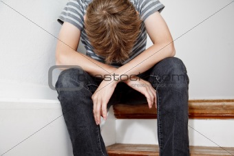 Boy crying while sitting on the stairs