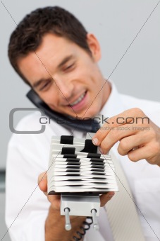 Businessman on phone and consulting a card holder
