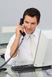 Attractive businessman on phone and working with a computer
