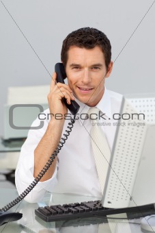 Smiling businessman on phone and working with a computer