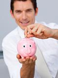 Attractive businessman saving money in a piggybank