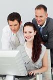 Smiling businesswoman and two businessmen using a computer