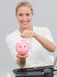 Smiling businesswoman saving money in a piggibank