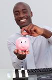 Happy Afro-American businessman saving money in a piggybank