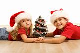 Kids on the floor with a decorated tree and christmas hats