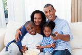 Smiling Afro-american family eating popcorn and watching TV