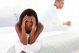 Upset Afro-american couple sitting on bed separately
