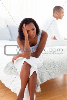 Angry couple sitting on bed separately 