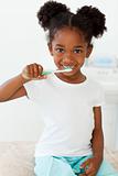 Portrait of a smiling little girl brushing her teeth