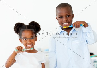 Smiling brother and sister brushing their teeth 