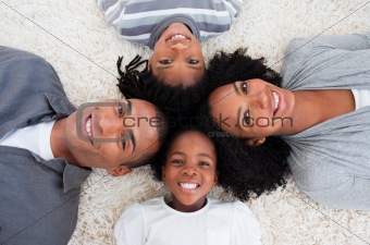Smiling Afro-American young family lying on floor in a circle