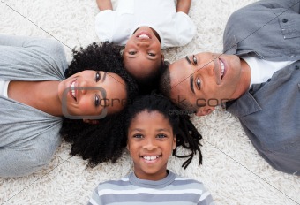 Smiling Afro-American young family lying on floor