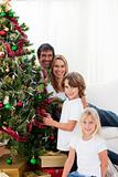 Happy family decorating a Christmas tree with baubles