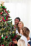 Smiling family decorating a Christmas tree