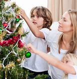Children hanging Christmas decorations with their mother