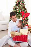 Smiling father and his daughter opening Christmas gifts