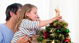Young girl putting star on Christmas tree