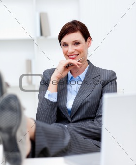 Attractive businesswoman leaning feet on desk 