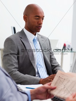 Businessman reading a newspaper with his colleague workig at a c
