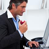 Close-up of a happy businessman eating a red apple