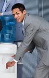 Attractive businessman filling cup from water cooler 