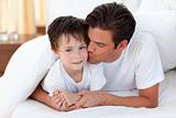 Father kissing his son lying on bed