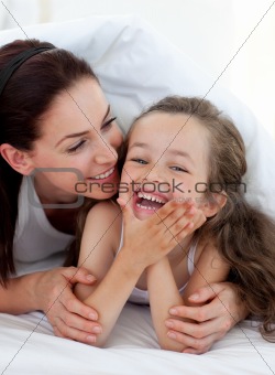 Little girl and her mother having fun on bed