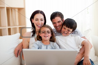 Smiling fanily using a laptop on the sofa