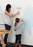 Mother and daughter painting wall together