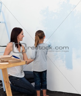 Mother and daughter painting wall together