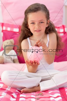 Girl saving money in a piggy bank in her bedroom