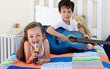 Little boy playing guitar and his sister singing