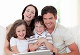 Smiling family using a laptop in the living-room