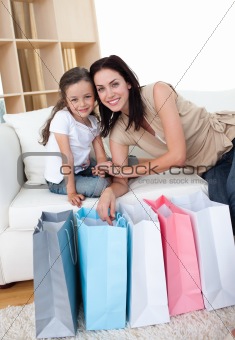 Smiling mother and her daughter opening shopping bags