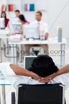 Businessman leaning back on a chair in front of his team 
